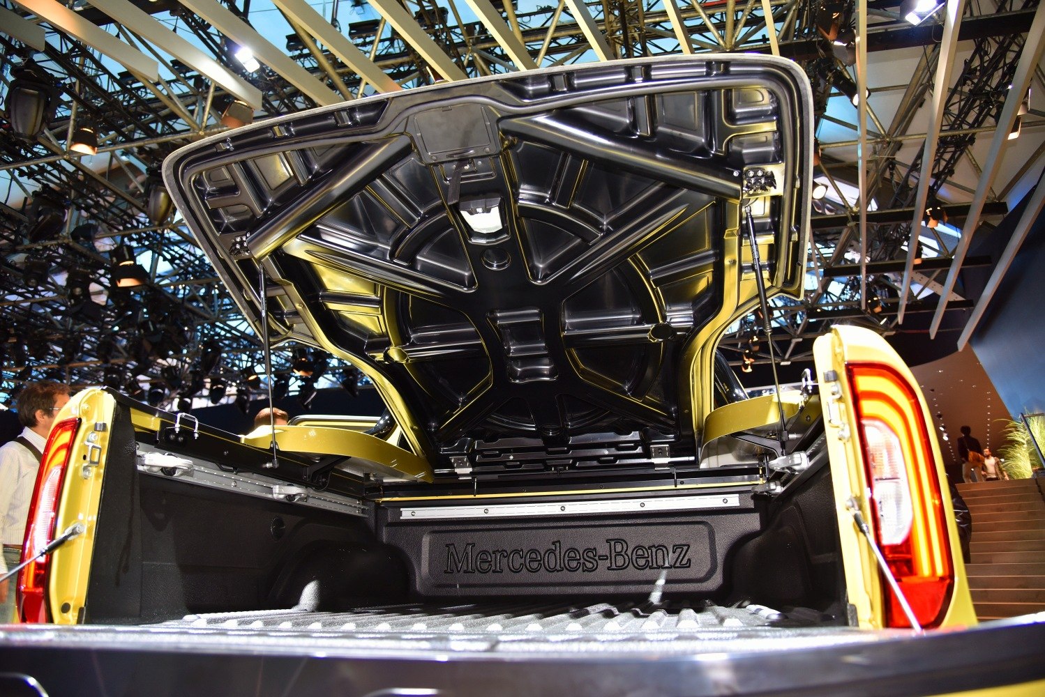 Pickup truck bed with open hard tonneau cover and rear lights.