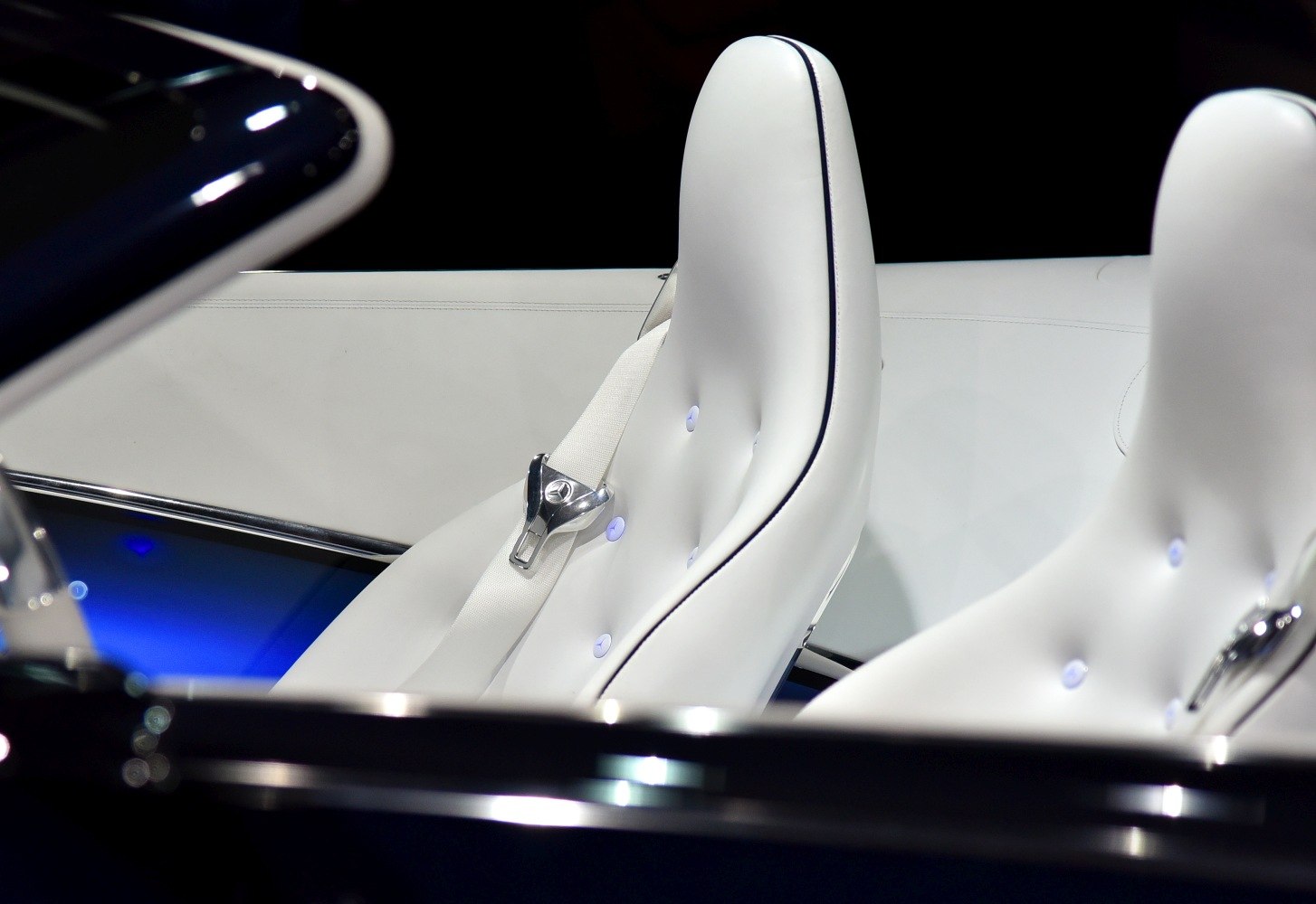 White leather seats with button tufting and branded metal seatbelt clasp
