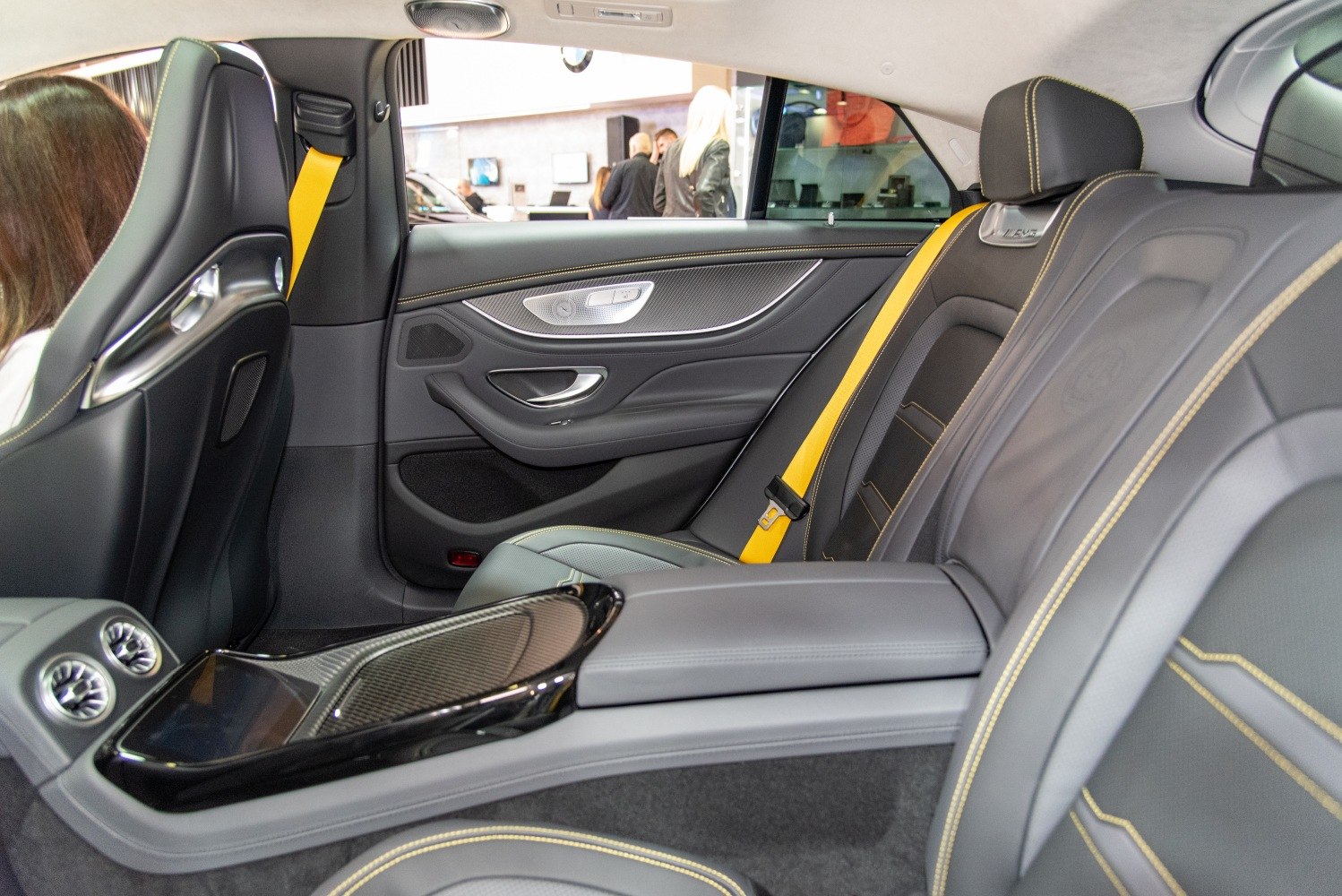 Luxury 4-door coupe interior with black leather seats and yellow seat belts