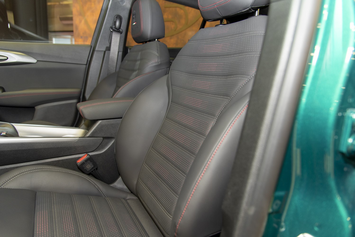 Close-up of leather seats with red stitching and armrest in a car interior