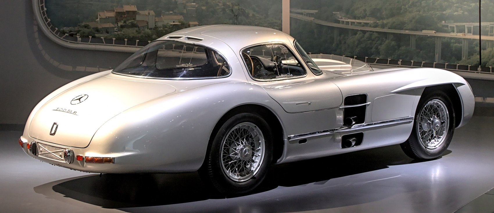 Aerodynamic silver racing coupe with wire-spoked wheels and smooth flowing lines.