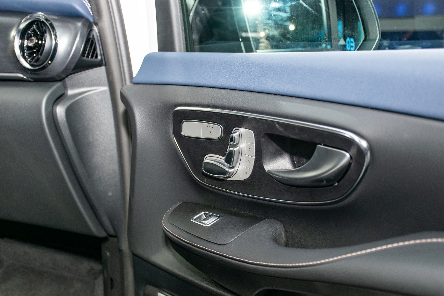 Car door interior with window switch, seat adjustment controls, air vent