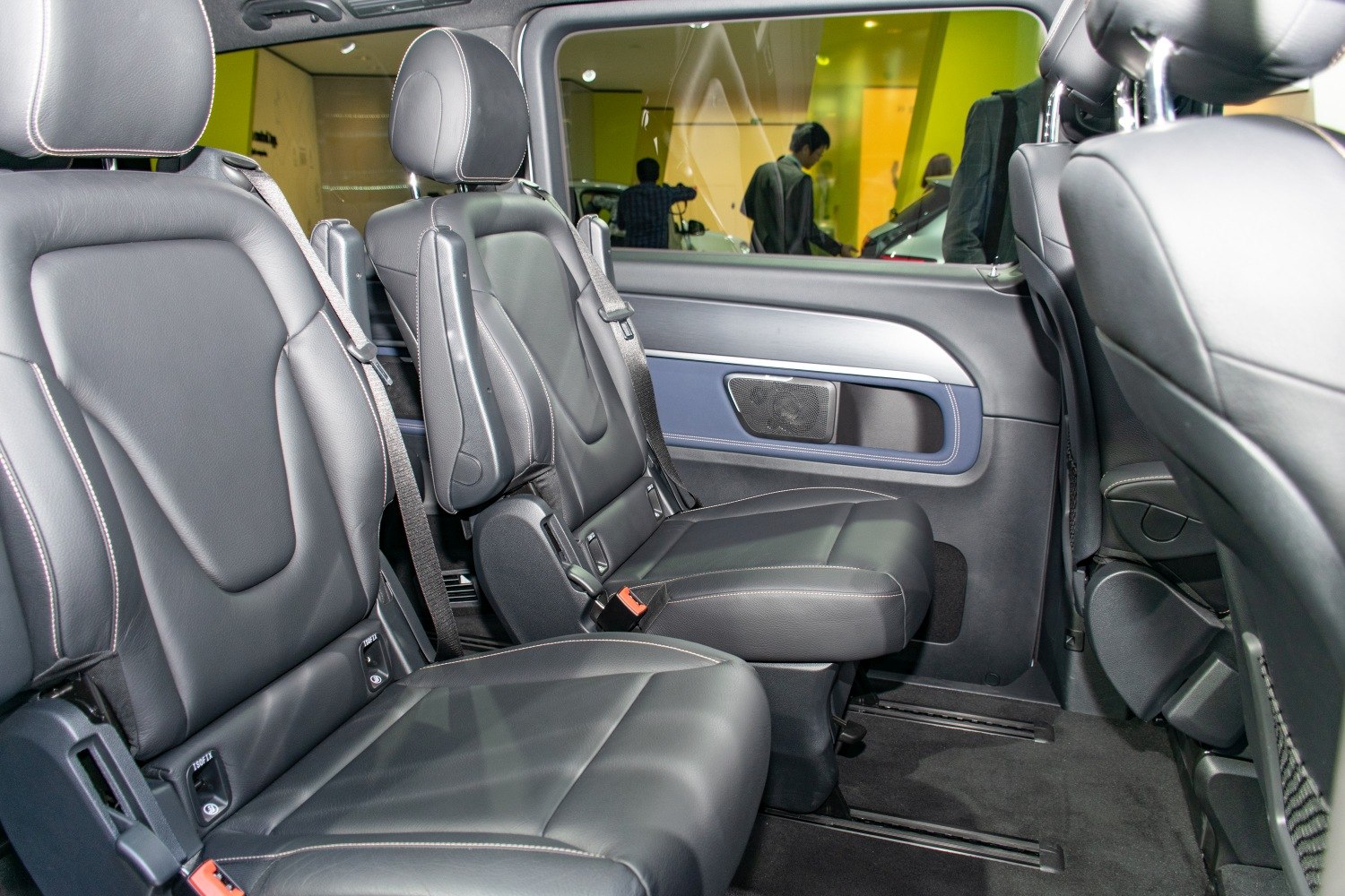 Black leather passenger seats with armrests and seatbelts inside a vehicle