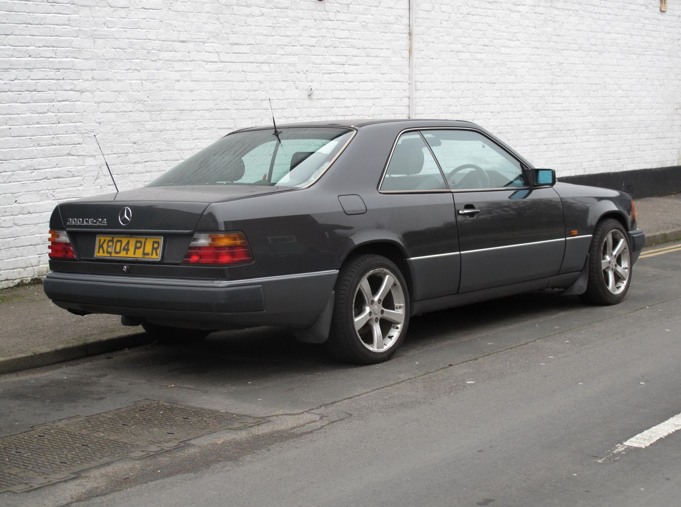 Dark gray coupe showing rear side profile with alloy wheels and distinctive rear lights