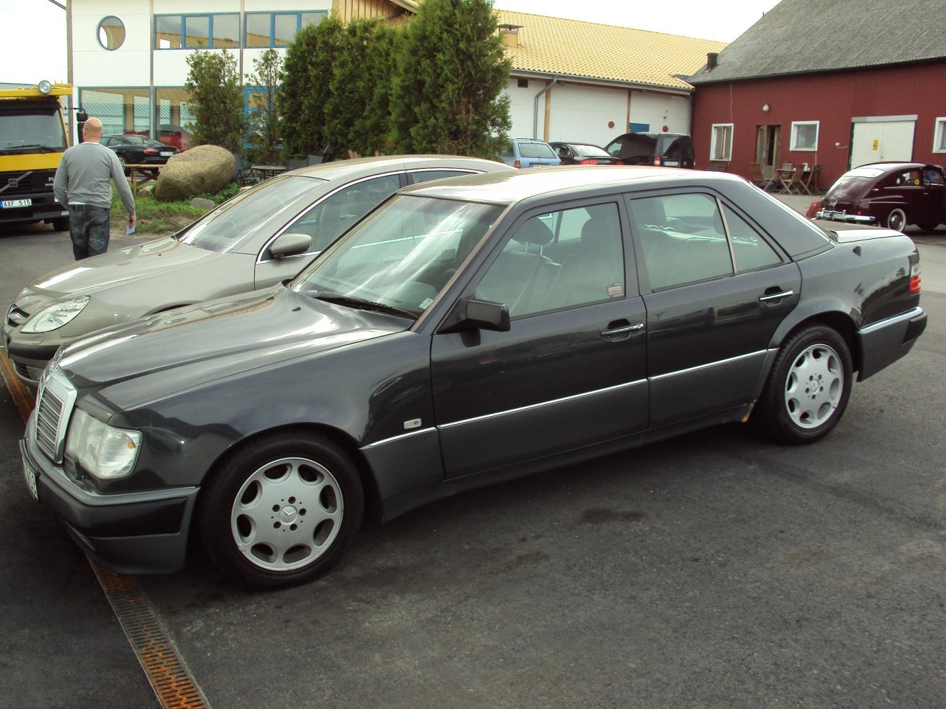 Boxy dark sedan with classic alloy wheels parked in a lot