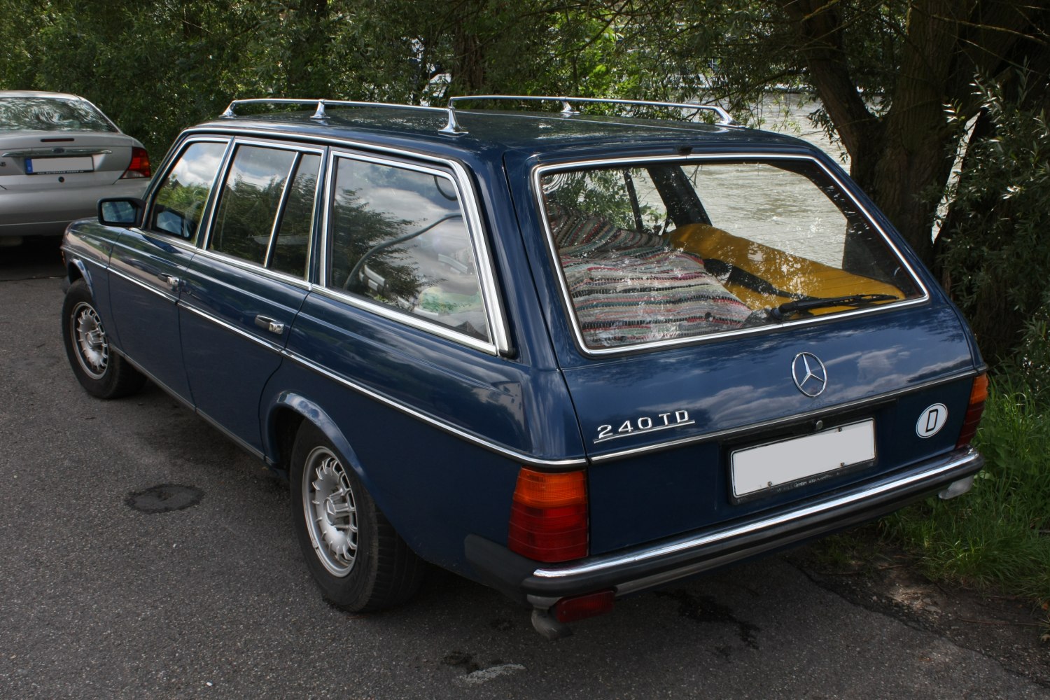 Rear and side view of a classic blue vintage station wagon with roof rails.