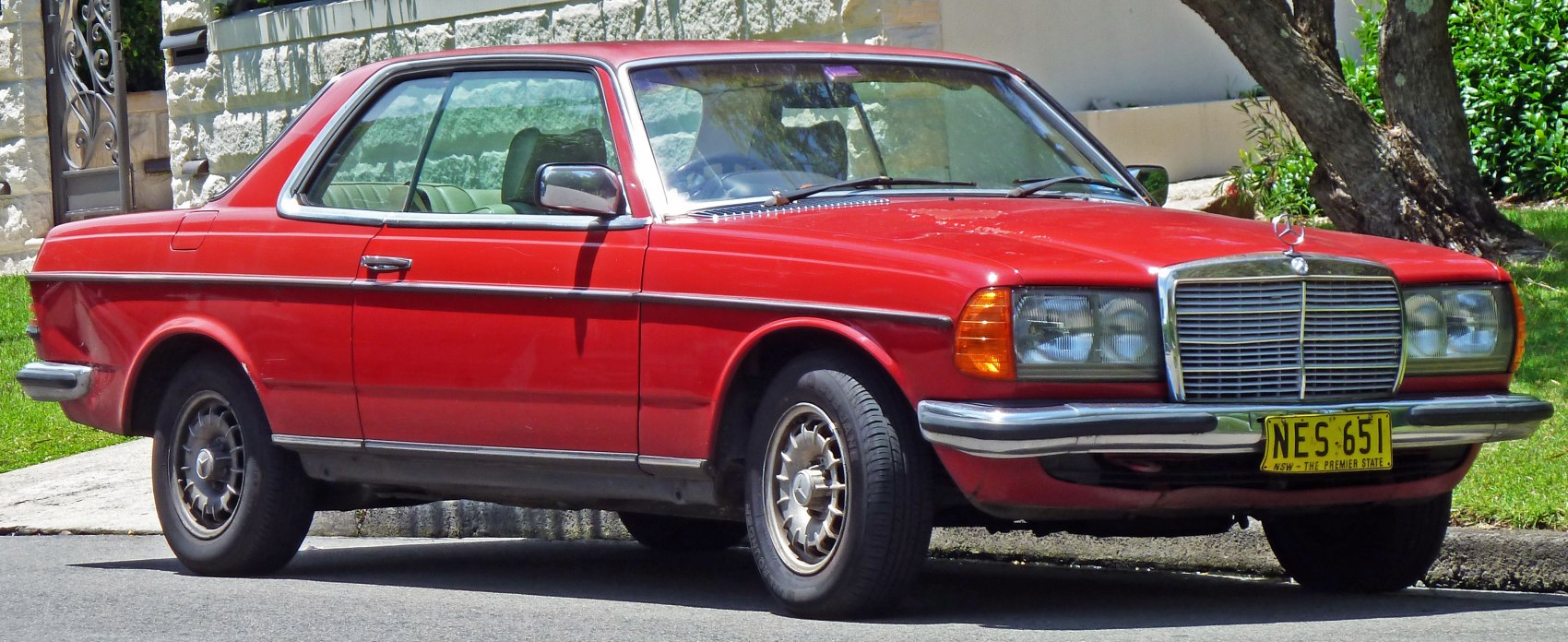 Vintage red two-door coupe with chrome grille and rectangular headlights