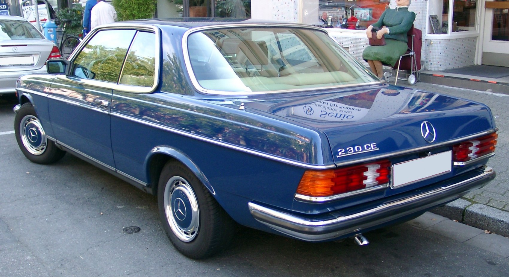 Rear-side view of blue classic coupe with chrome trim and distinct taillights