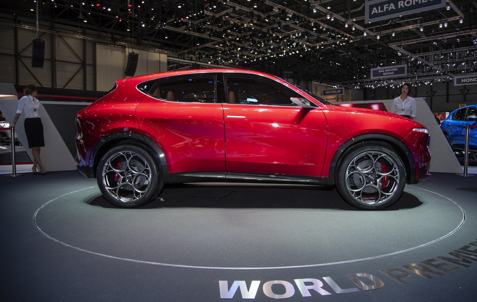 Side view of a red SUV with large circular-design wheels.