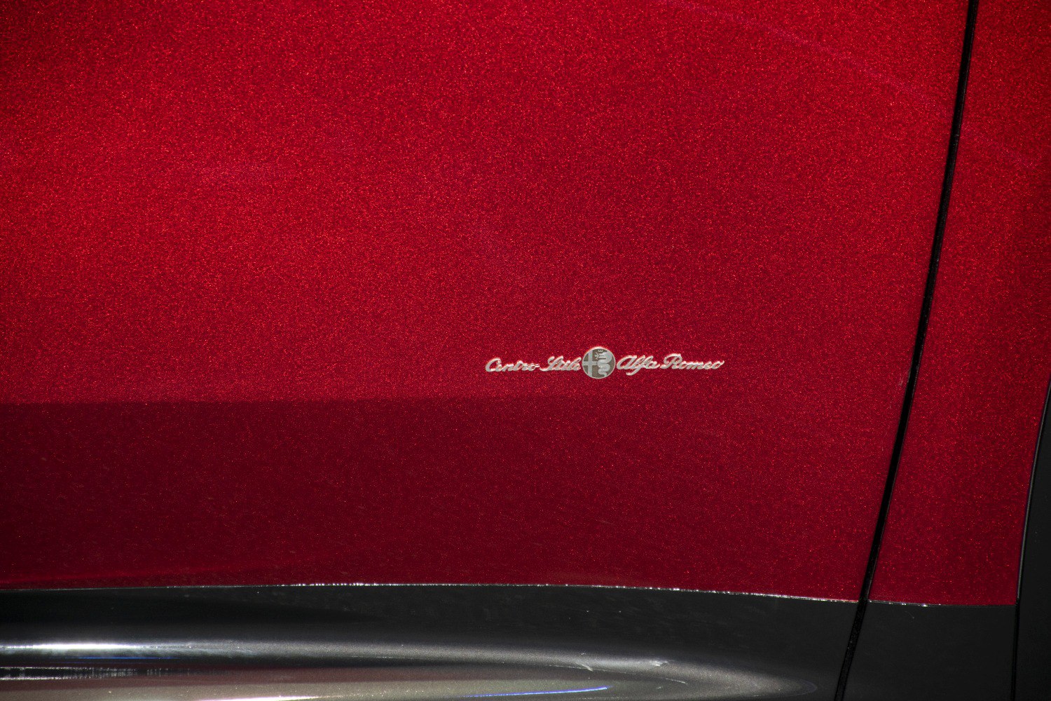 Close-up of Alfa Romeo emblem on red metallic body with black trim