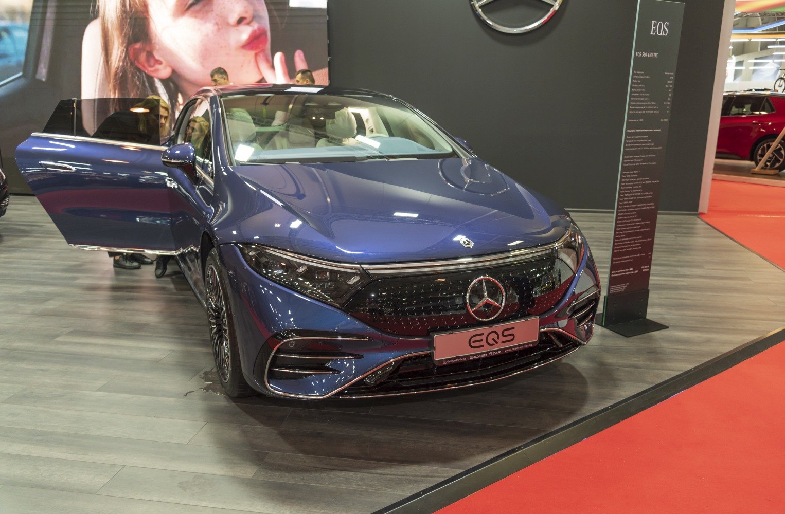 Front view of electric luxury sedan with open door and illuminated grille
