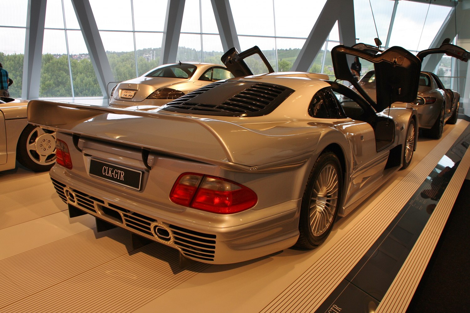 Rear view of a car with prominent rear wing and gull-wing doors open