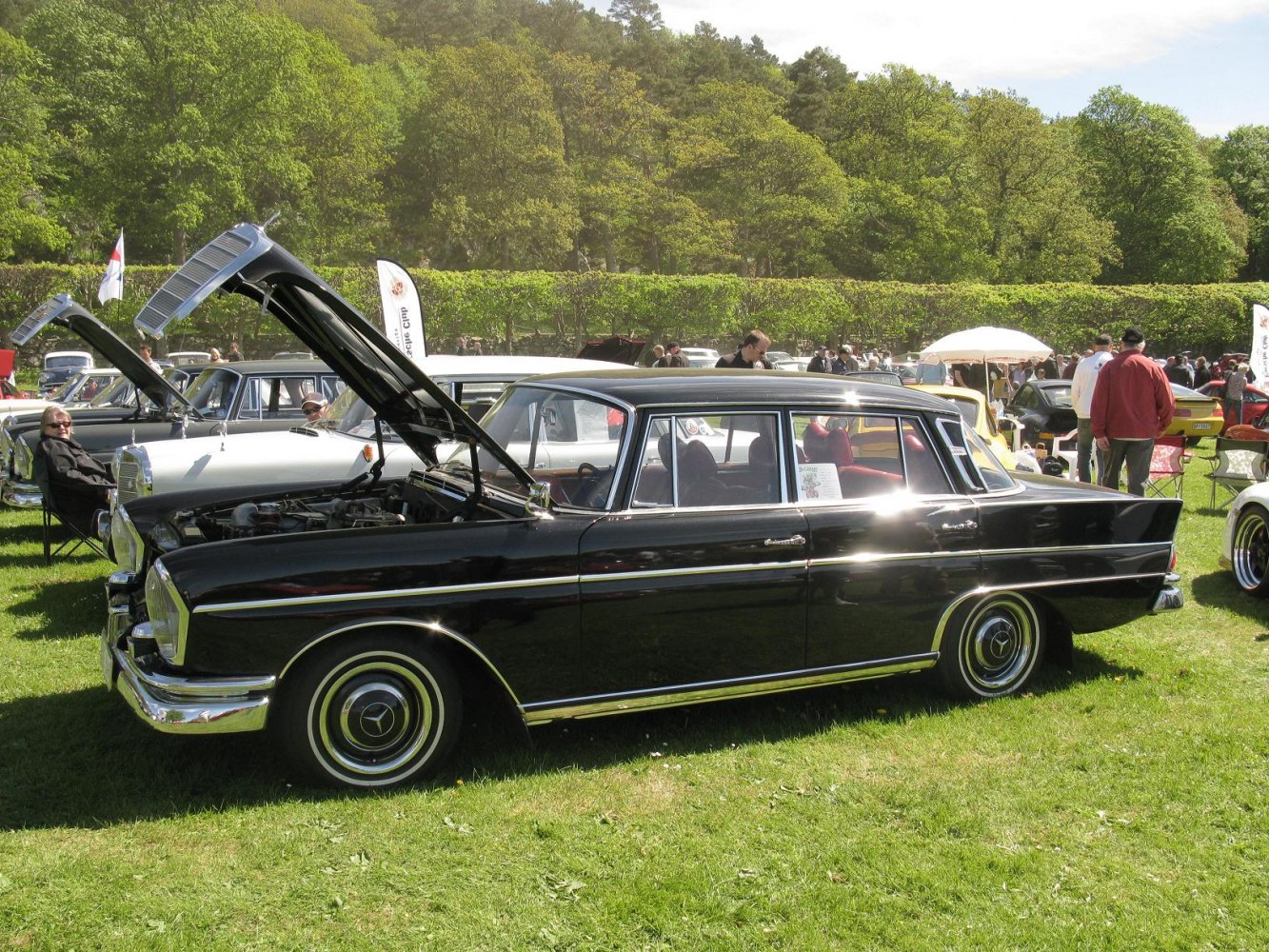 Black classic sedan with open hood at outdoor vintage car event