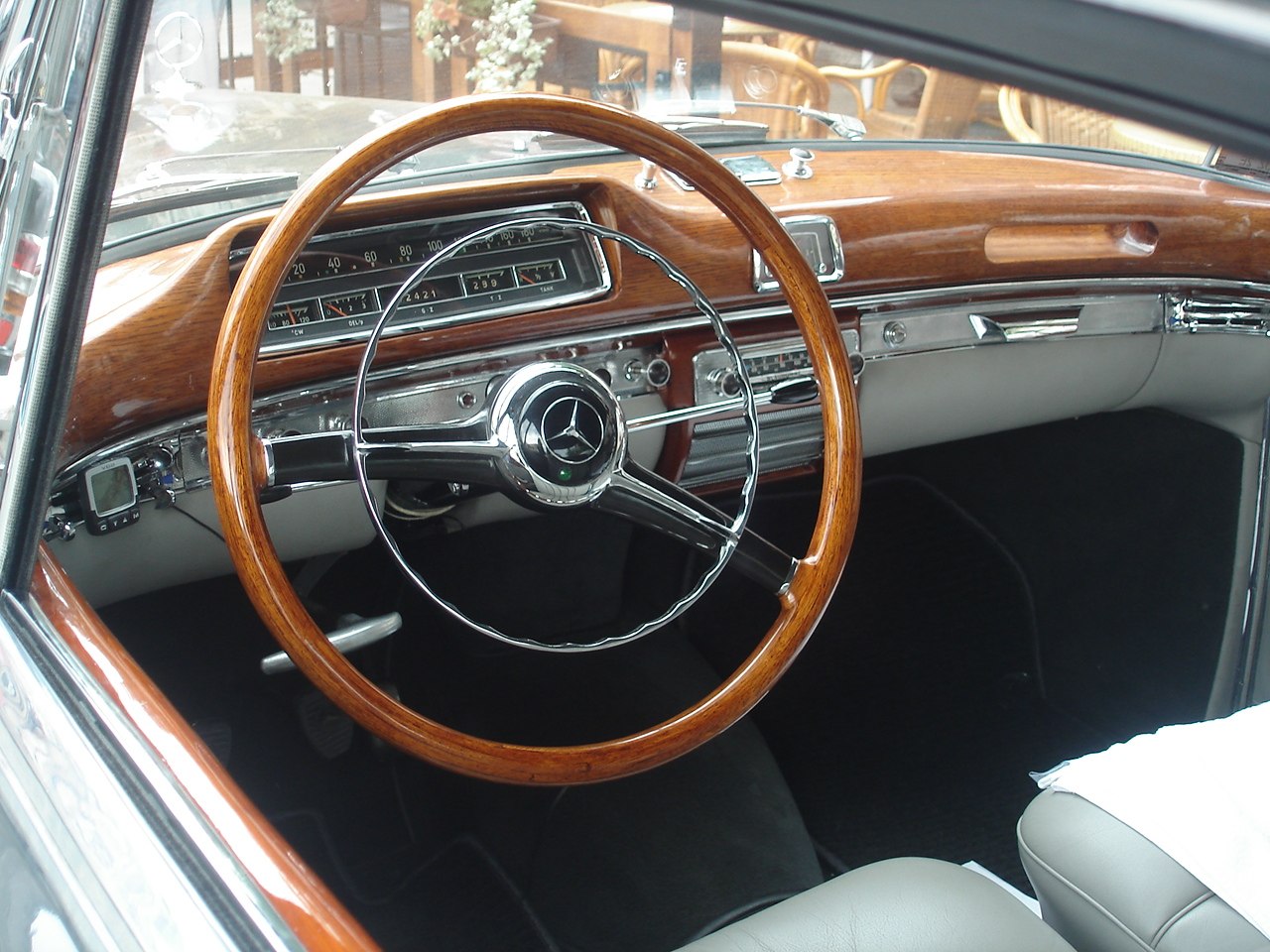 Wooden steering wheel with classic dashboard gauges and chrome trim