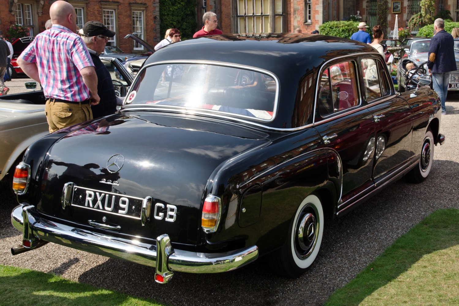 Curved rear design with chrome bumpers and classic whitewall tires.