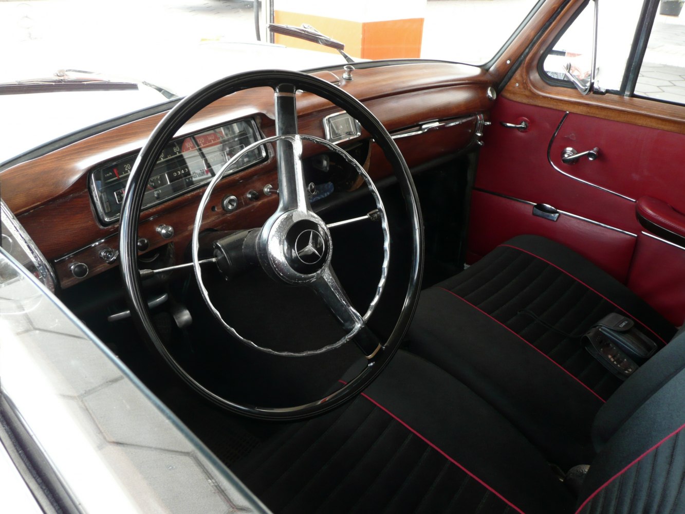 Classic vintage steering wheel and wood dashboard with red-trimmed upholstery