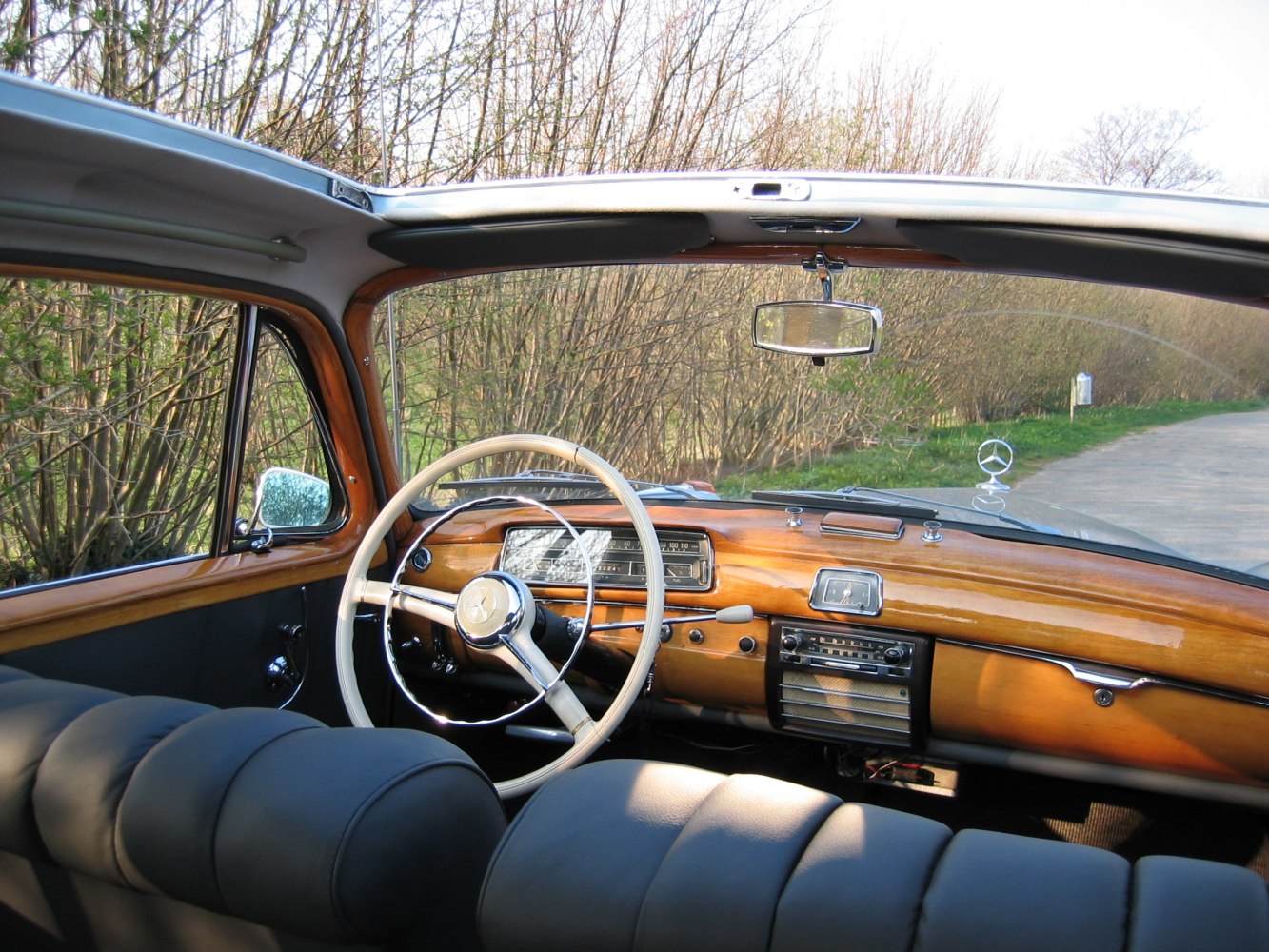 Classic wood dashboard and vintage steering wheel in a mid-20th century sedan interior