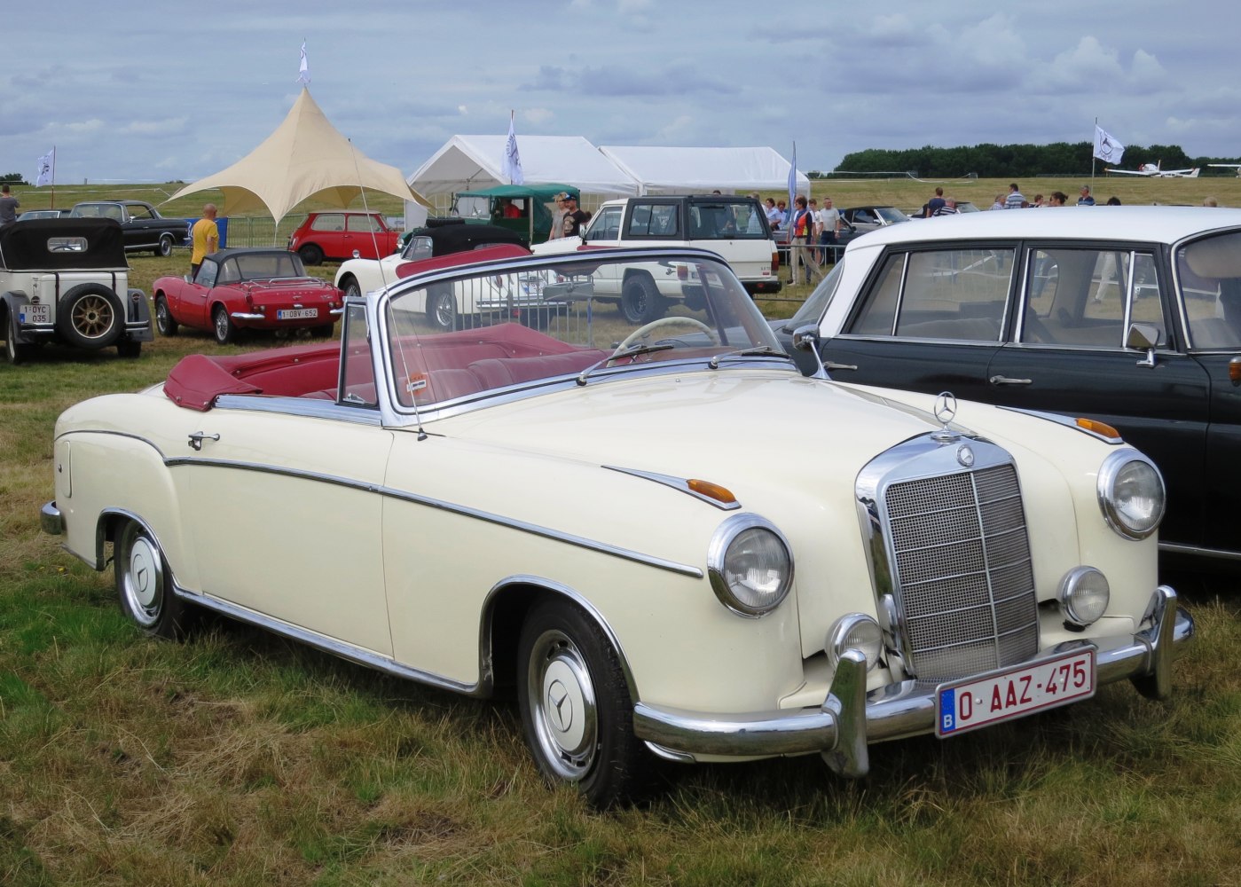 Convertible with round headlights and chrome grille, red interior, soft top.
