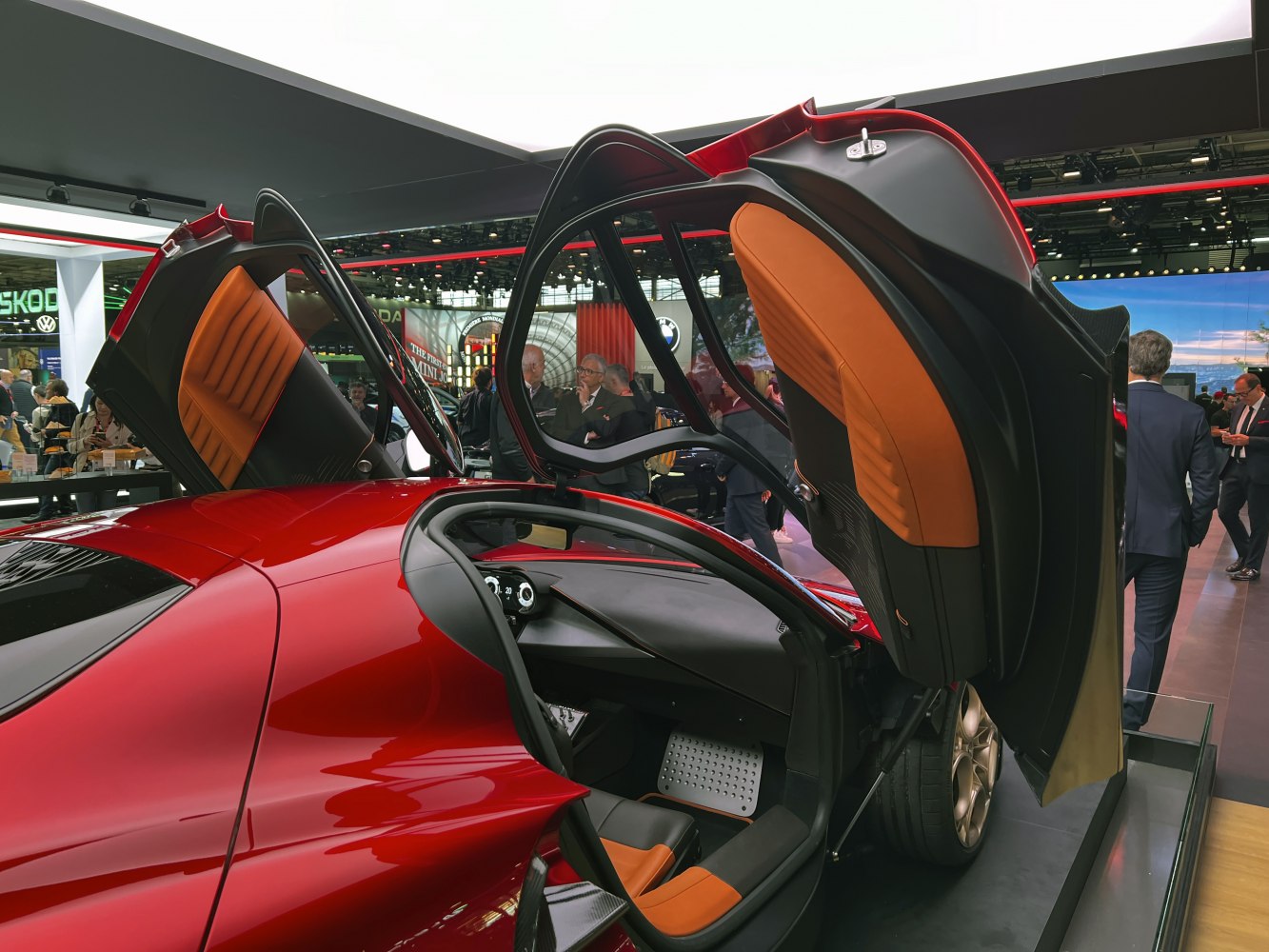 Butterfly doors open revealing orange-accented interior and driving controls