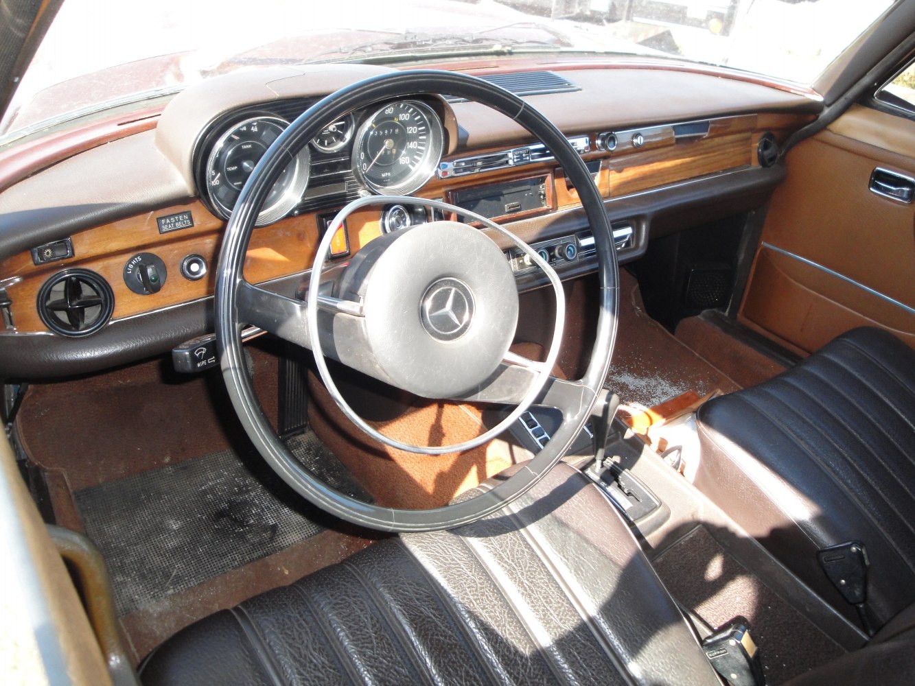 Vintage steering wheel and wood-trimmed dashboard with leather seats.
