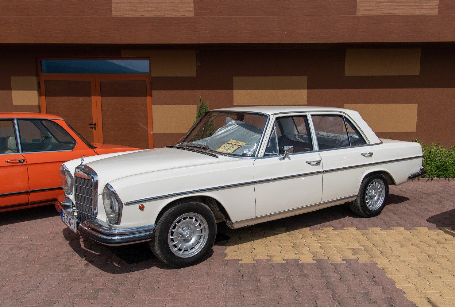 White classic sedan with chrome trim and distinctive grille from front side view