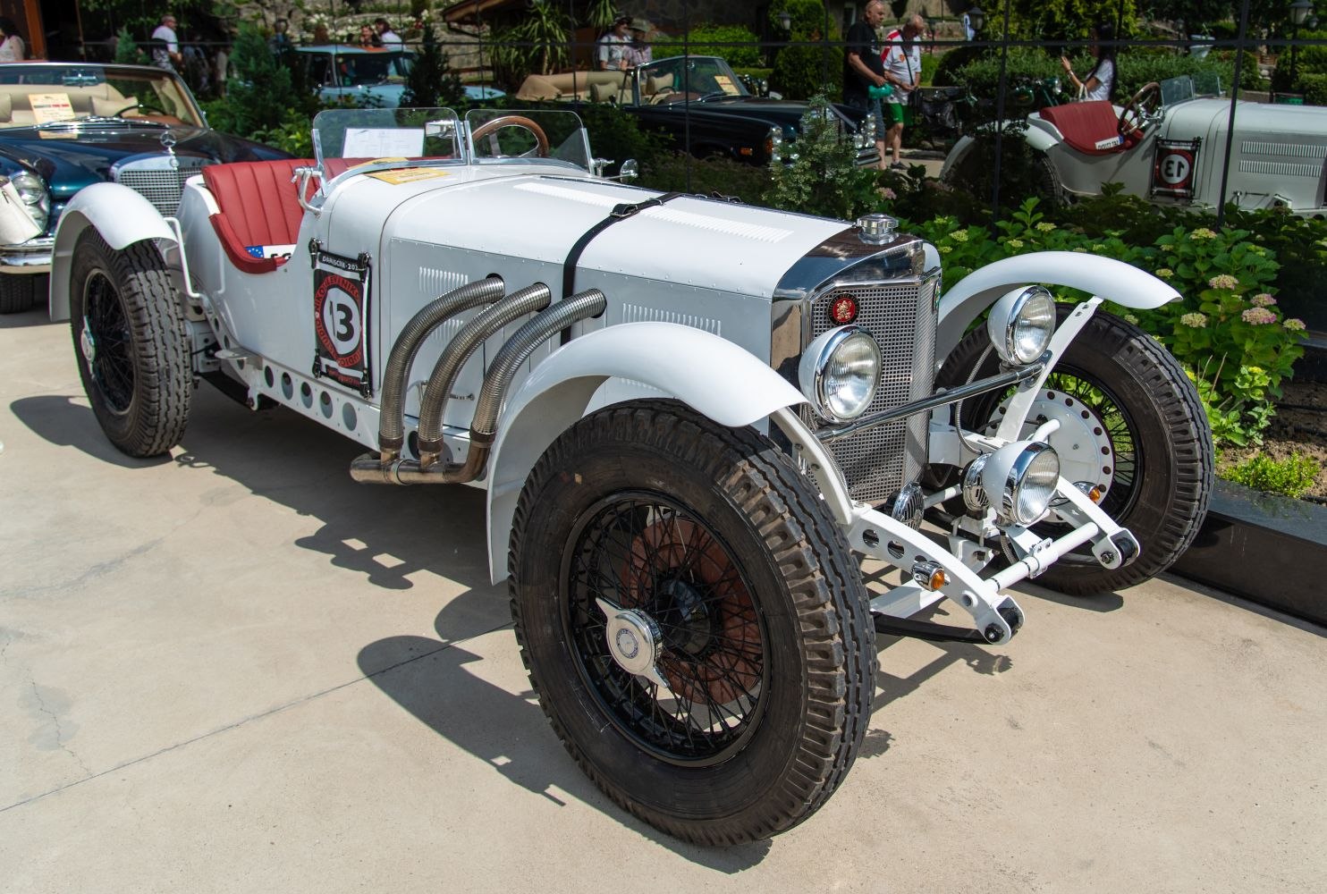 Vintage racing car with exposed side exhaust pipes and open cockpit.