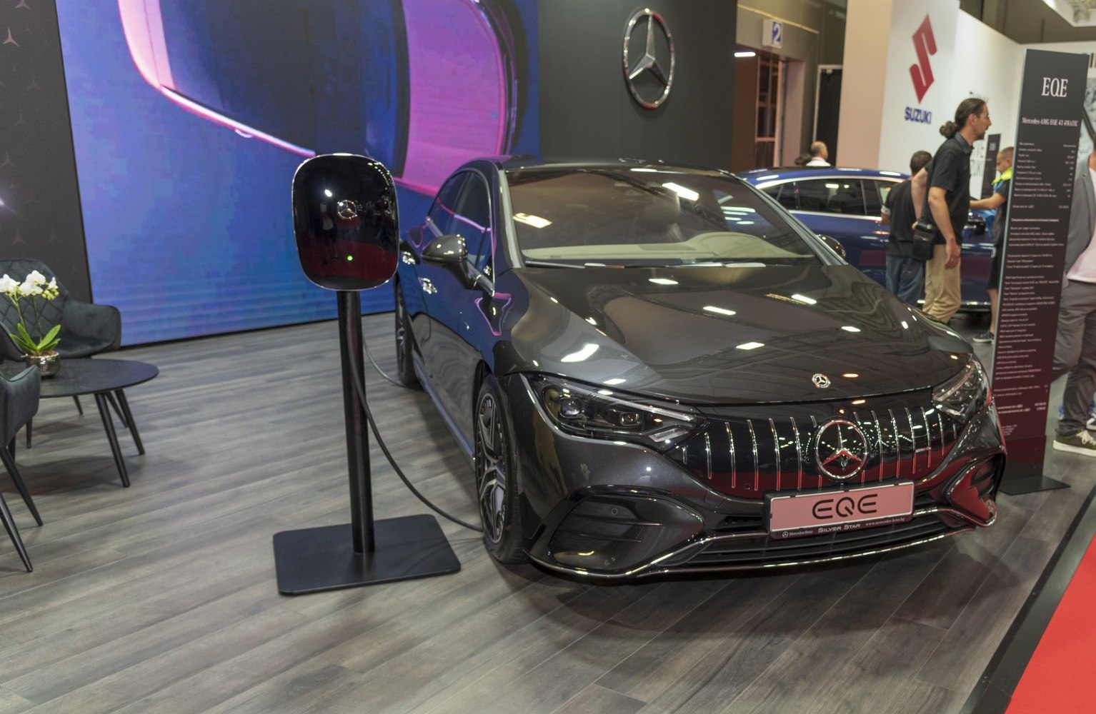 Electric sedan front view with charging station and glossy black finish