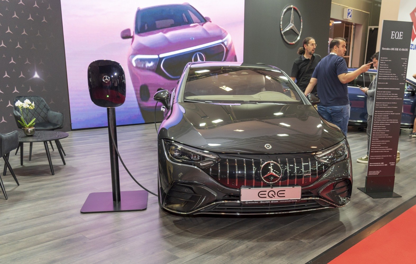 Front view of electric sedan at charging station, sleek grille and headlights