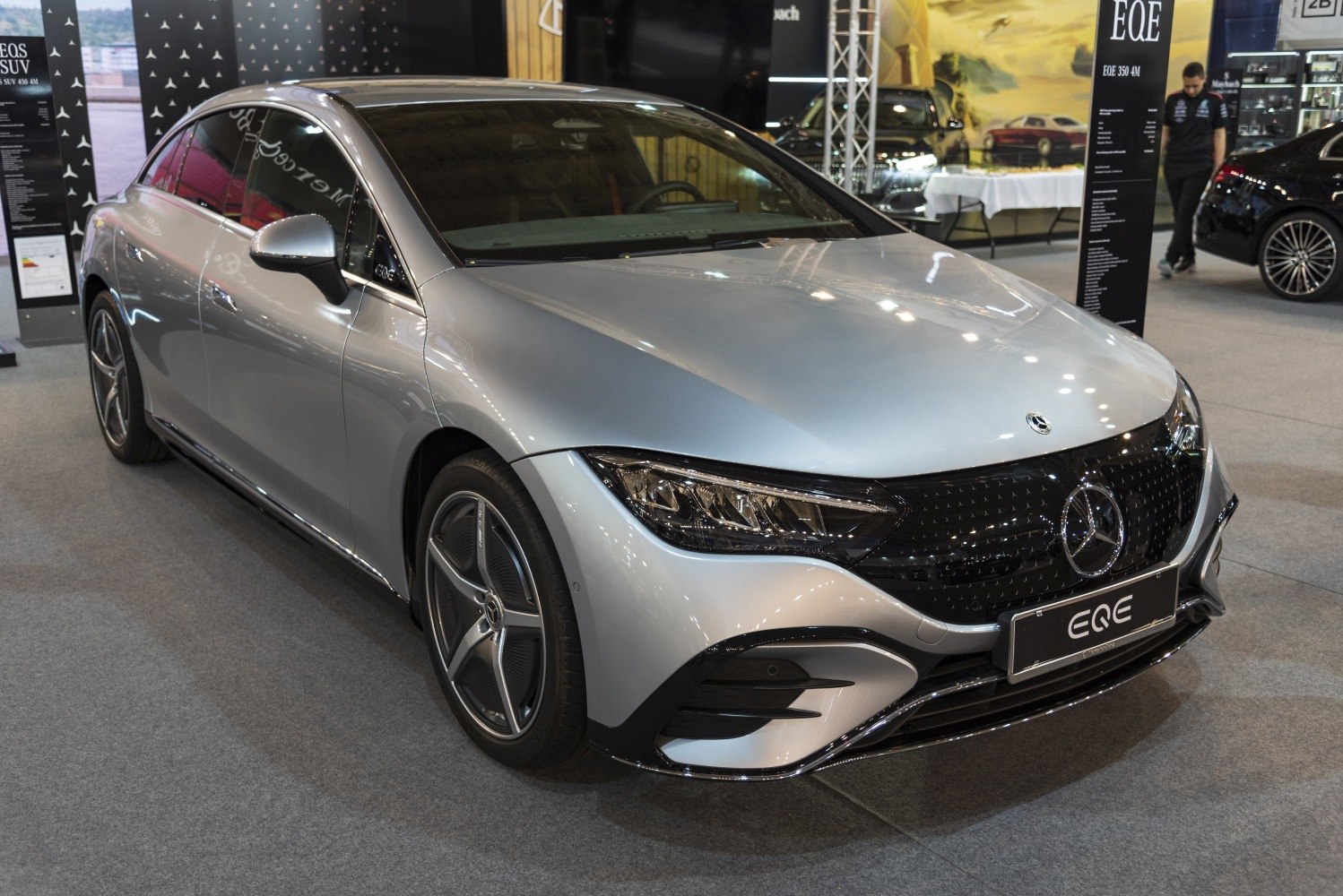 Front-side view of silver electric sedan with sleek headlights and distinctive grille.