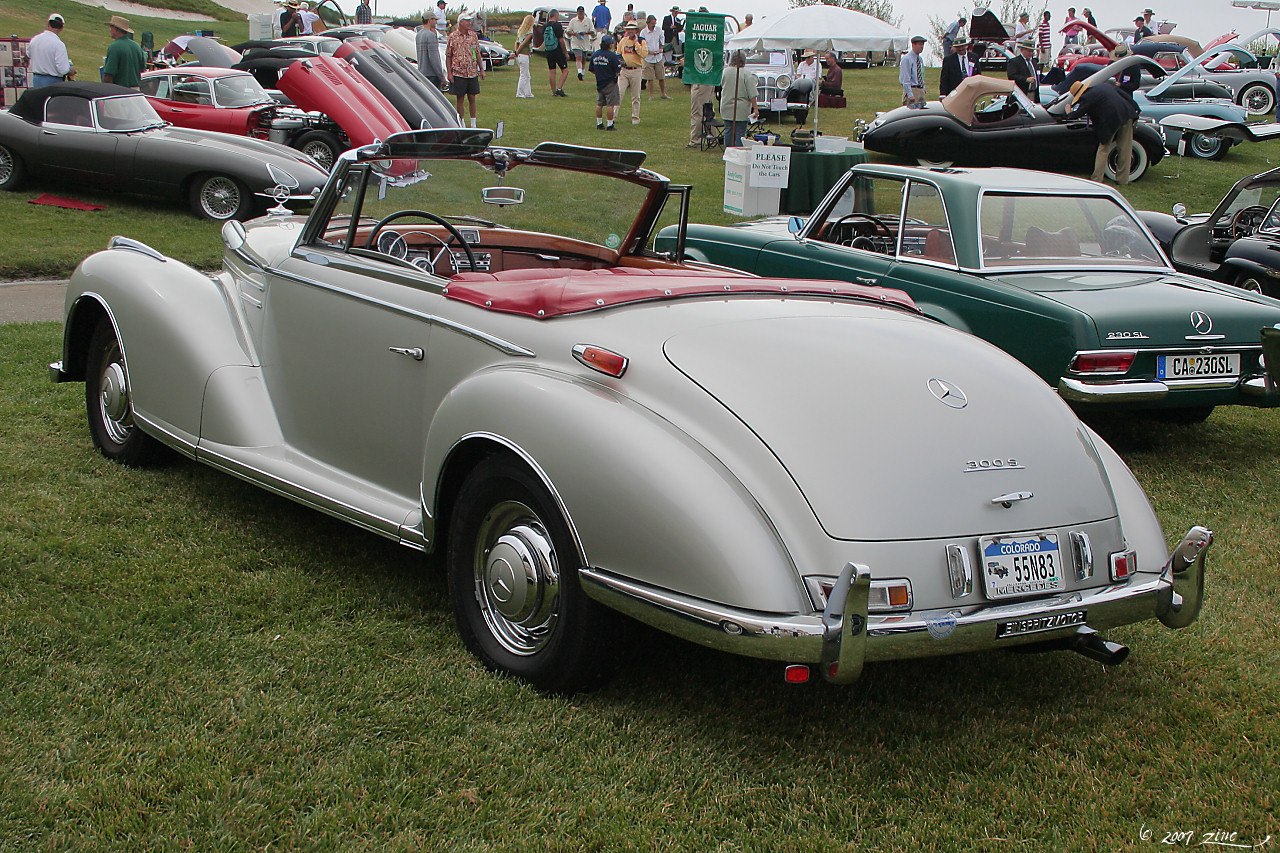 Convertible with smooth rounded rear fenders, chrome bumpers, and red leather interior.