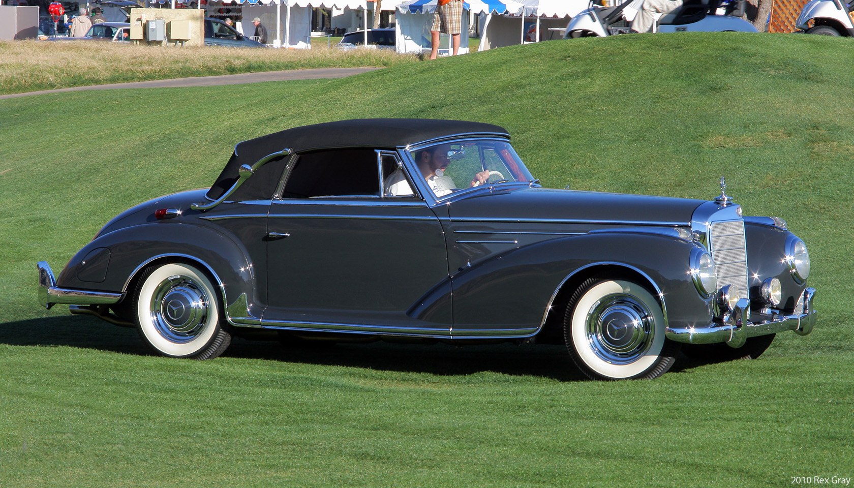 Vintage cabriolet with black soft top, whitewall tires, chrome bumpers and grille