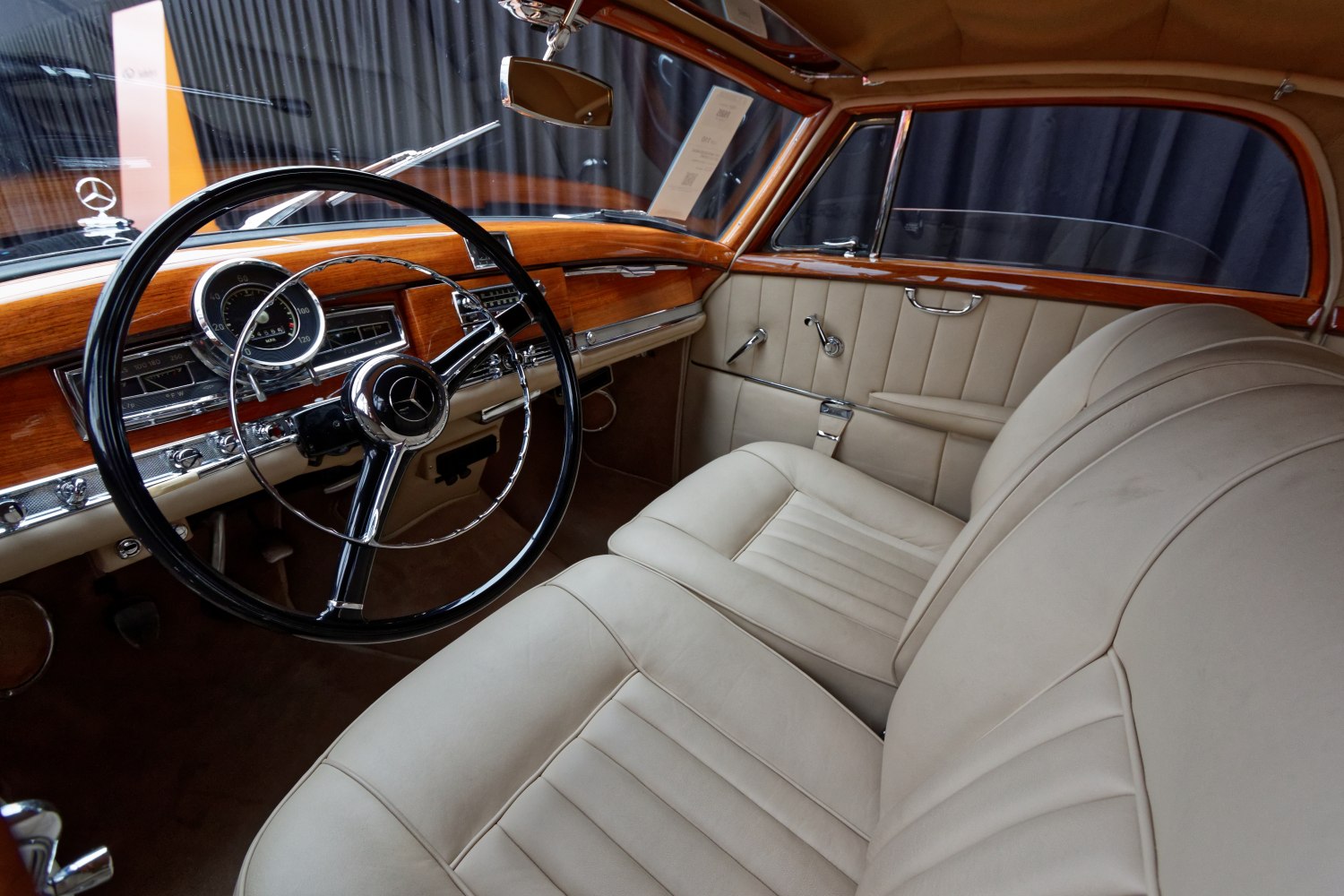 Vintage steering wheel and beige leather seats with wooden dashboard.