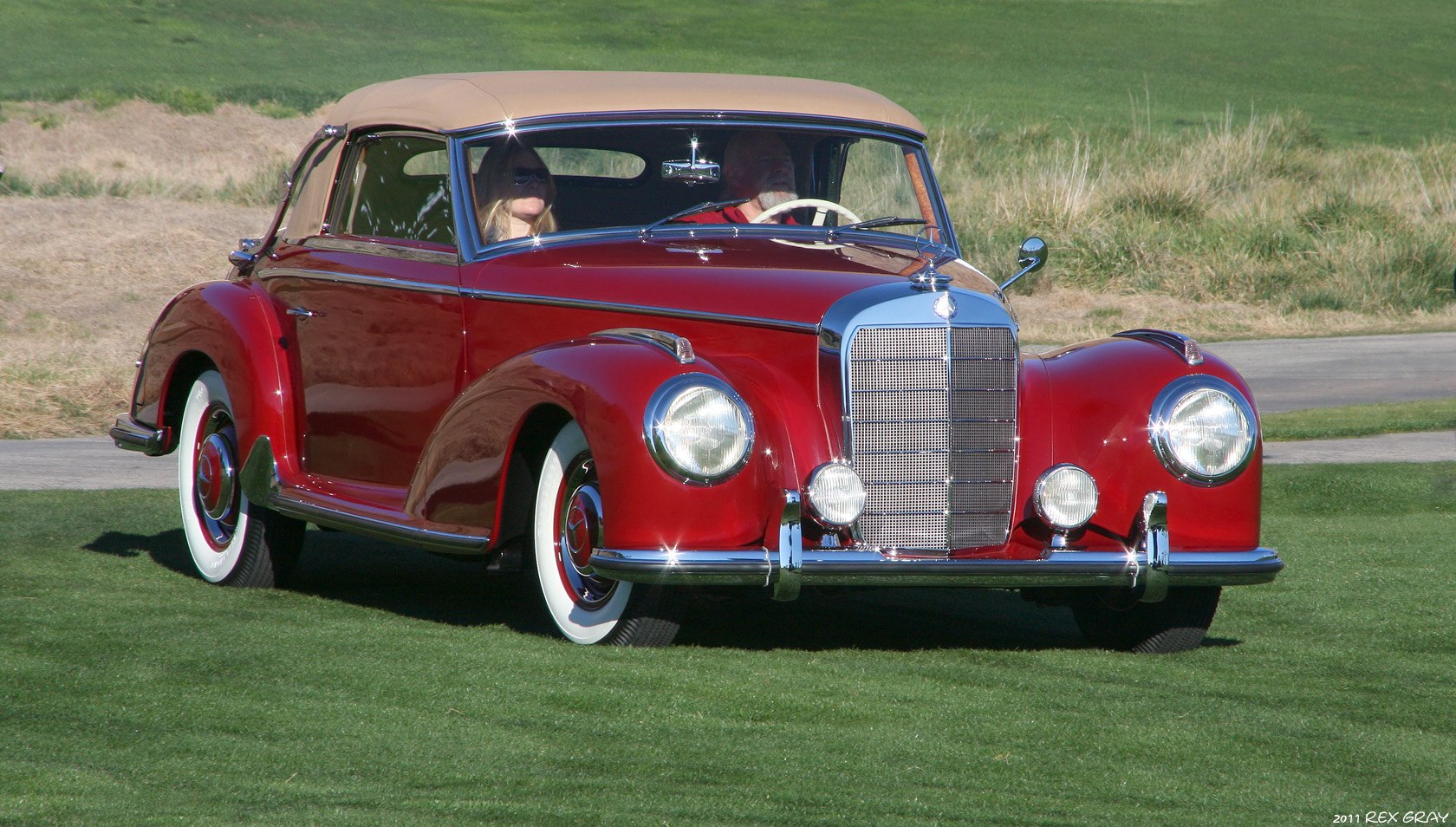 Vintage convertible with soft top, chrome grille, and whitewall tires.