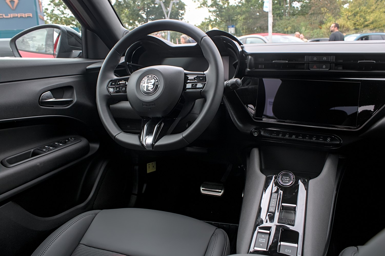 Steering wheel with controls, large touchscreen, center console with start button and drive mode selector