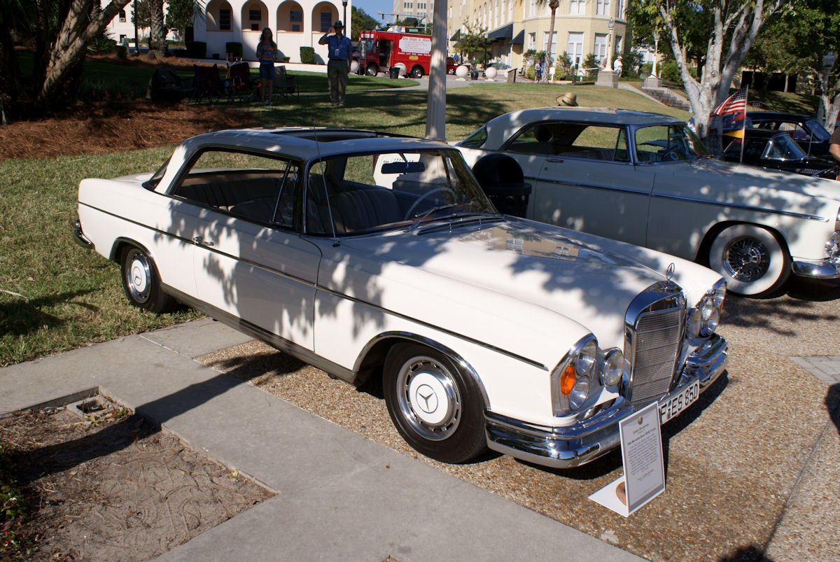White hardtop coupe with dual round headlights and large chrome grille