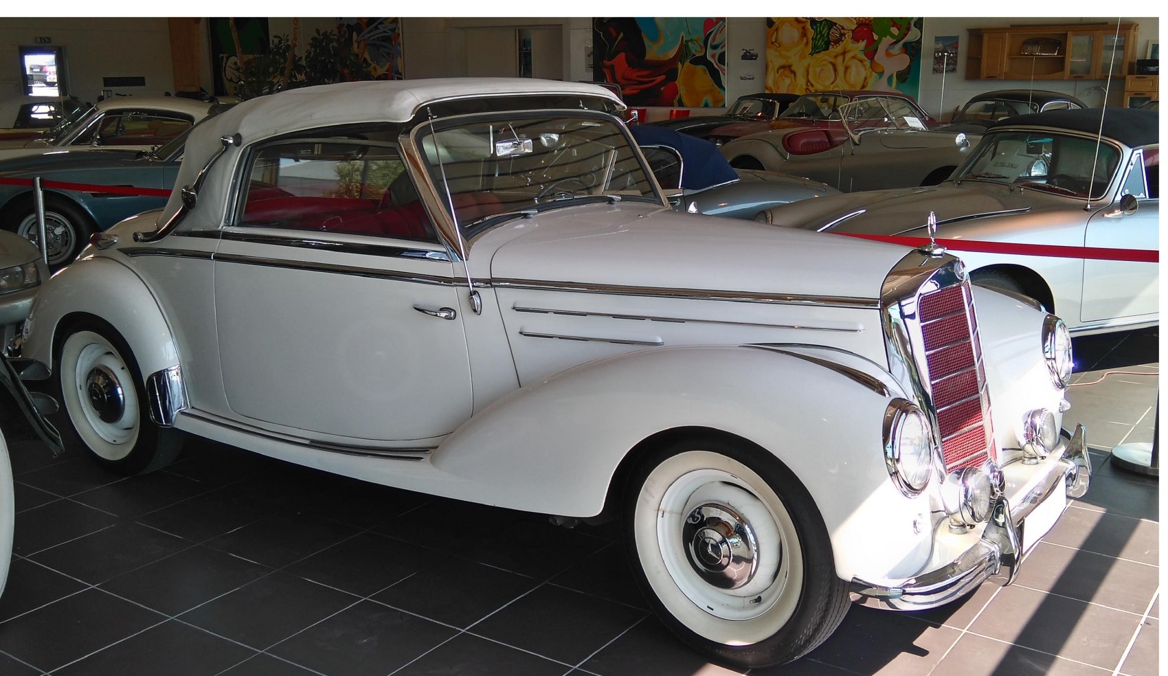 Vintage convertible with rounded fenders, whitewall tires, and soft top roof.
