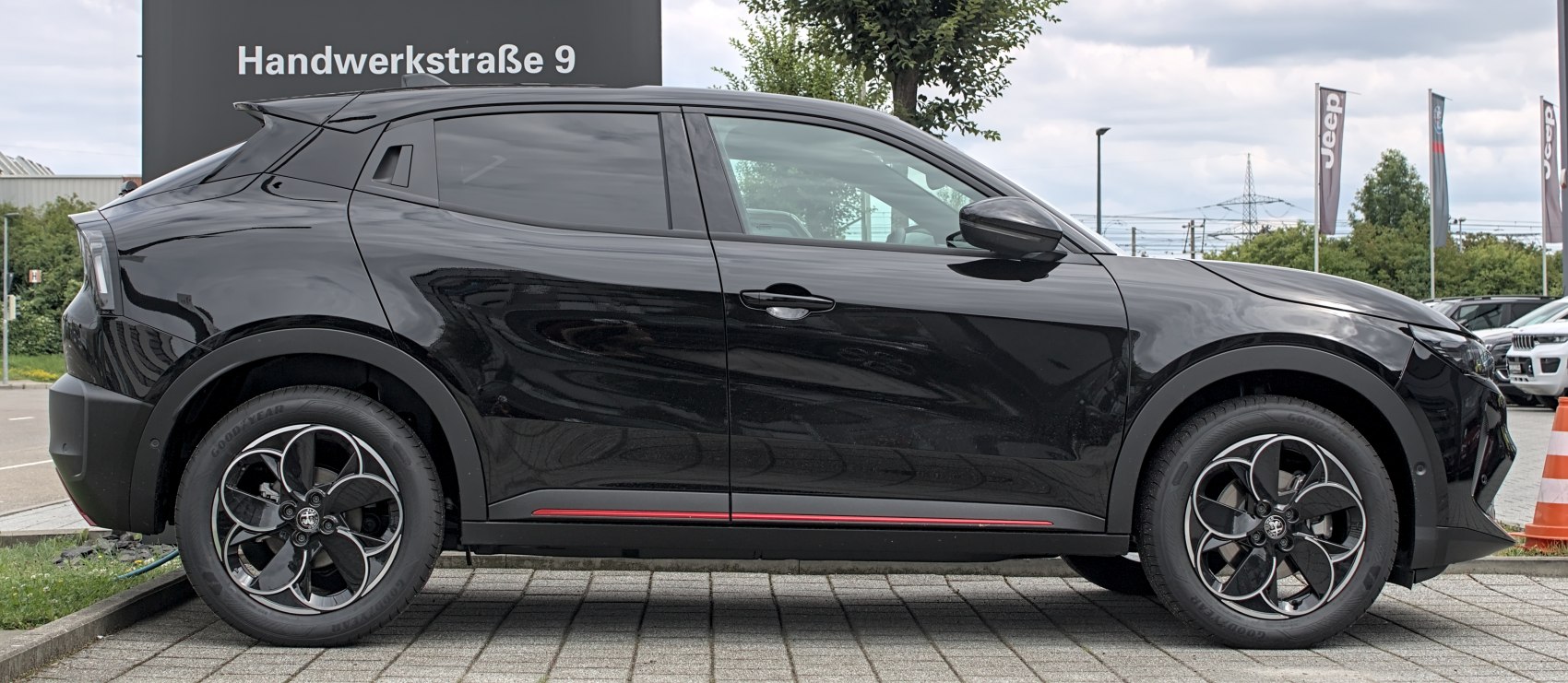 Side profile of a sleek black vehicle with distinctive alloy wheels.