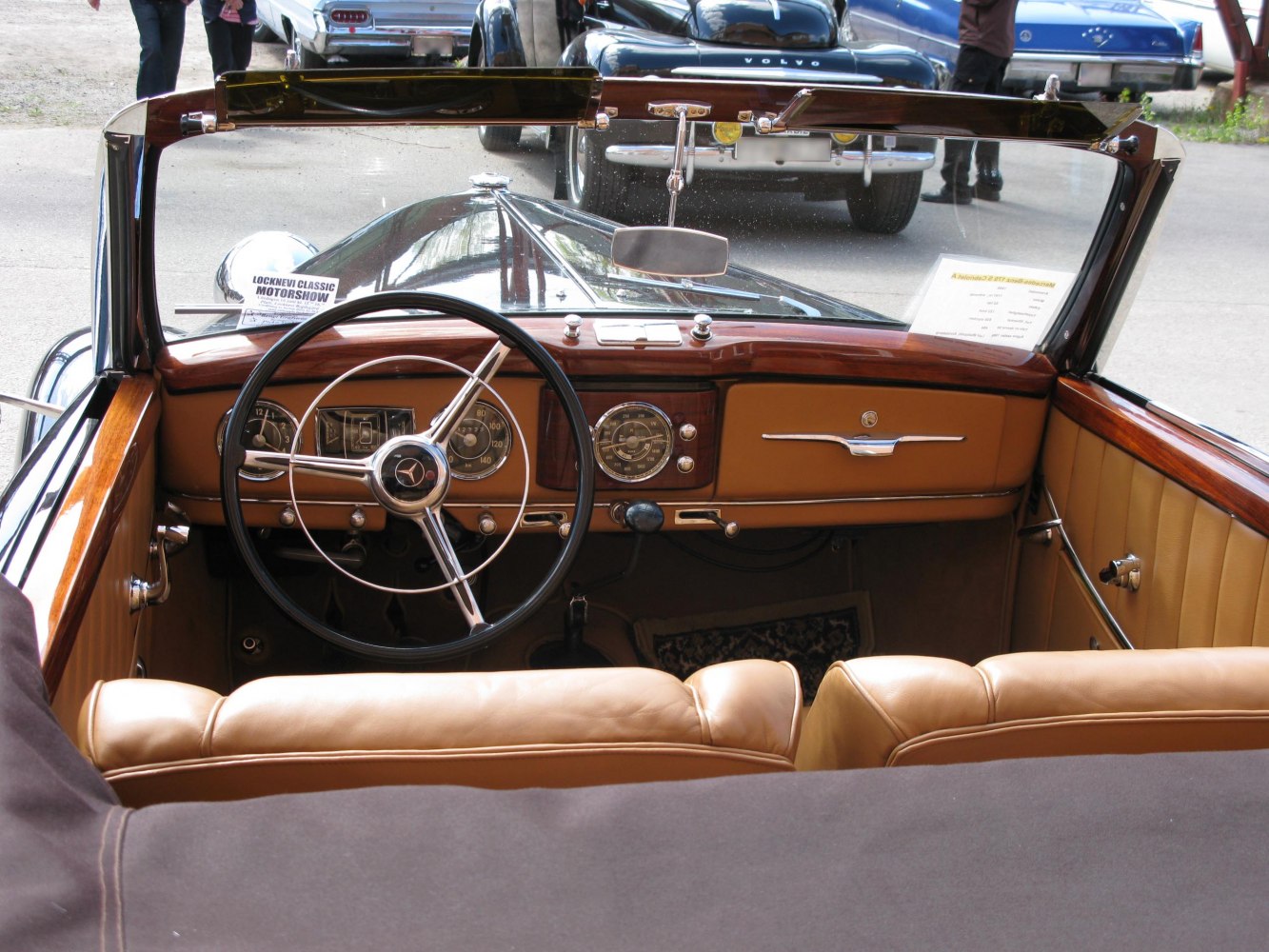 Vintage convertible interior with wooden dashboard and classic steering wheel.