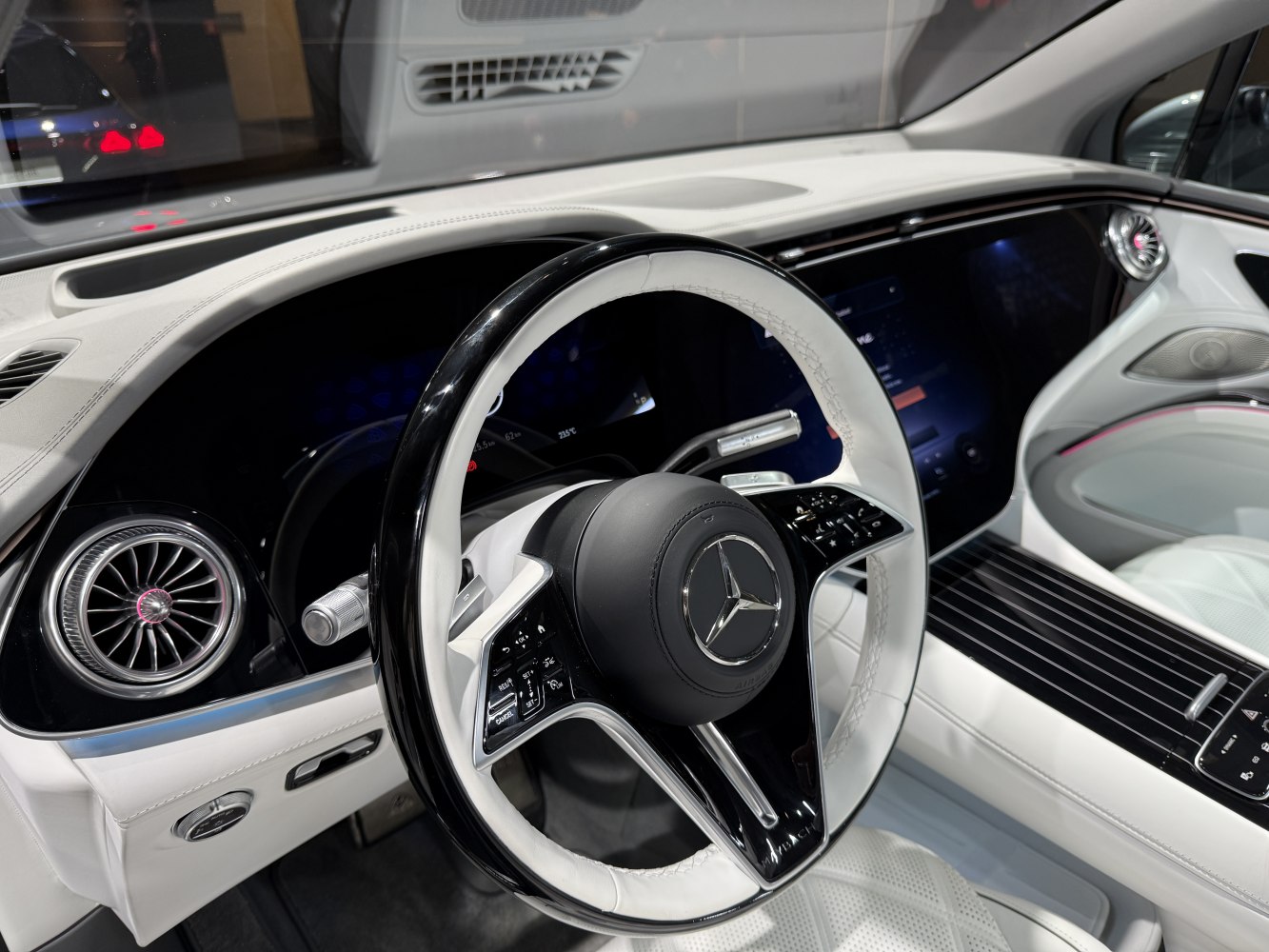 White leather steering wheel and digital dashboard with luxury air vents.