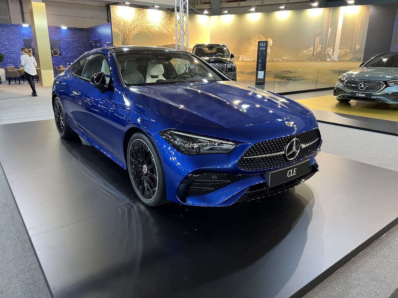 Luxury blue sports coupe with black multi-spoke wheels and aggressive front grille