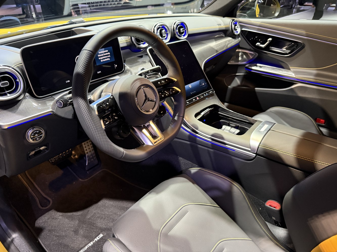Digital dashboard and AMG steering wheel with carbon fiber trim and ambient lighting.