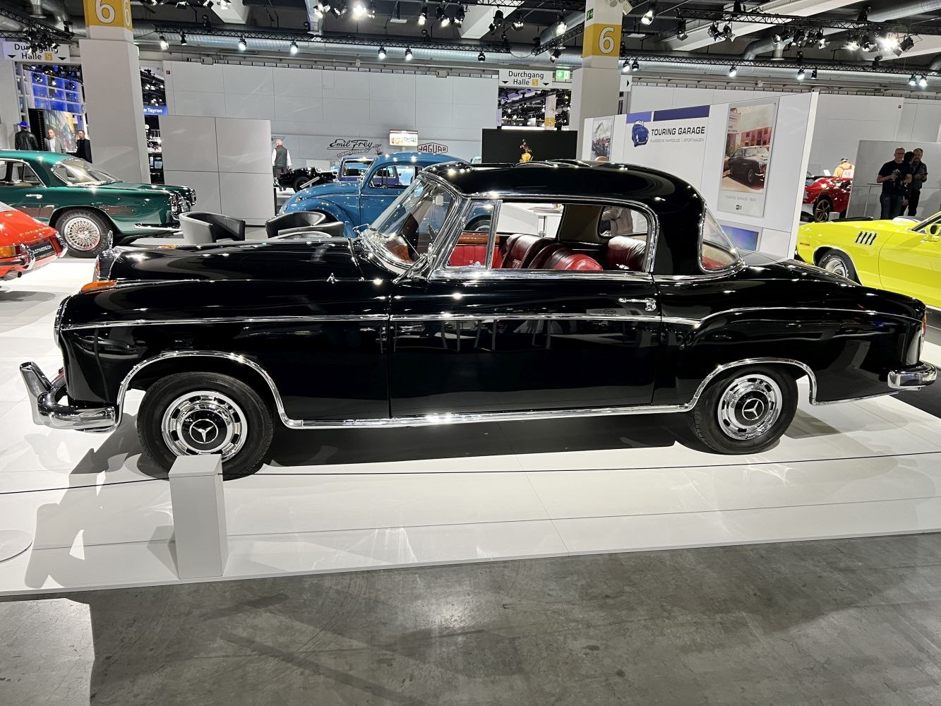 Sleek black classic coupe with chrome trim and vibrant red leather interior.