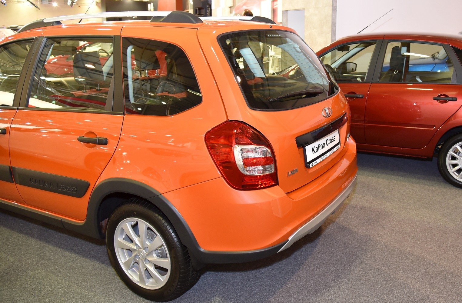 Rear and side view of an orange vehicle with prominent taillights and alloy wheels.