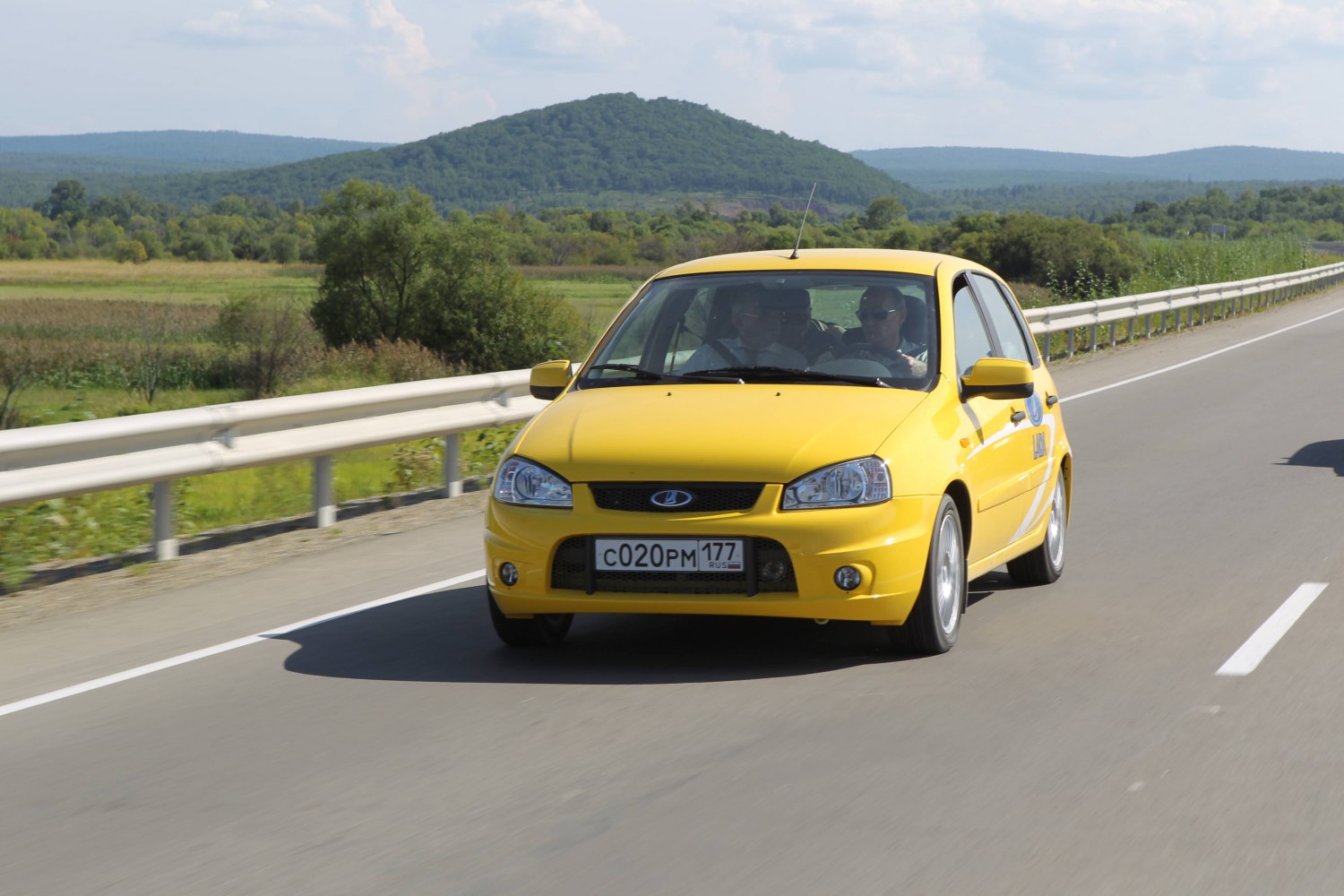 Yellow compact hatchback driving front view on highway