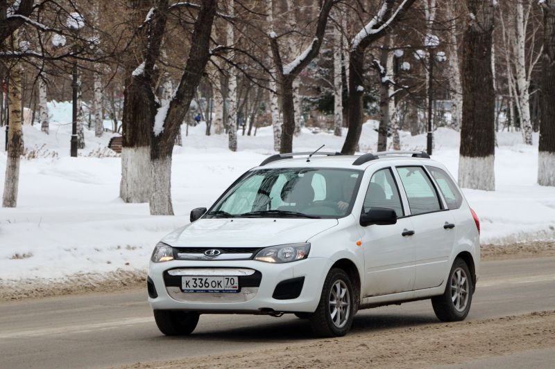 White station wagon driving on snowy road in winter