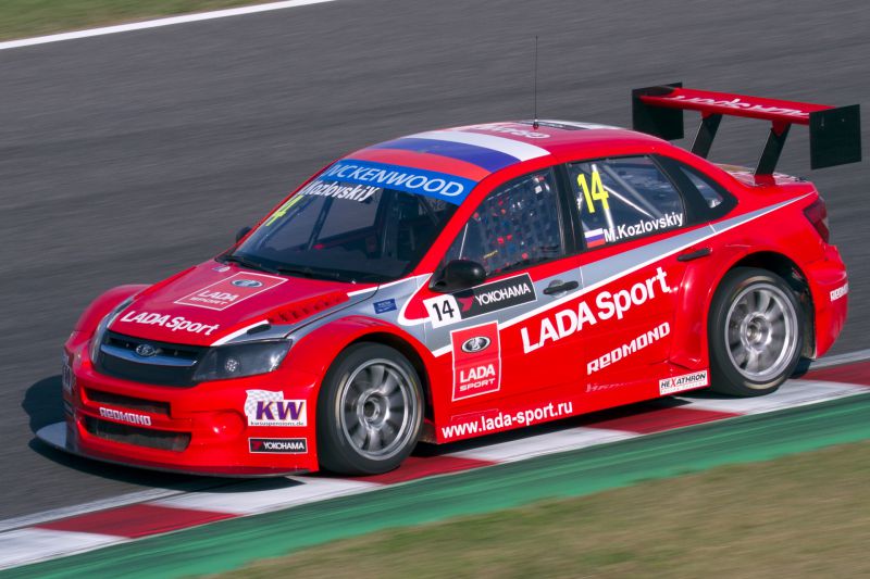 Red Lada Granta I Sport racing car with aerodynamic wing and racing decals.