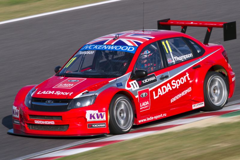 Race car with aerodynamic body kit and large rear wing on track.