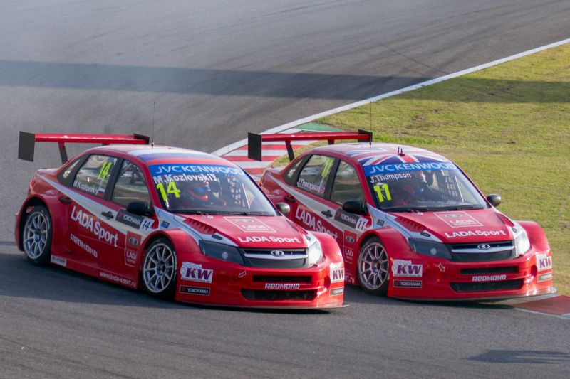 Two red Lada Granta I Sport racing cars with large rear wings on a race track