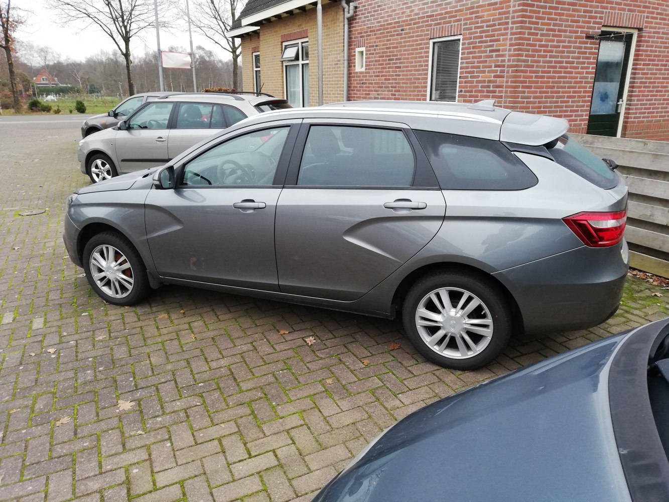 Gray station wagon with angular side contours, roof rails, and rear spoiler.