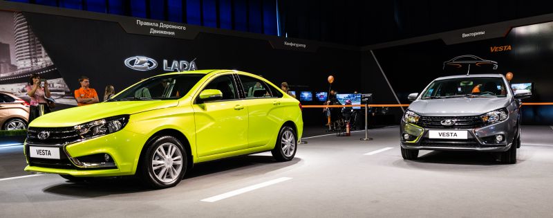 Two Lada Vesta sedans showing front and side views in a showroom.